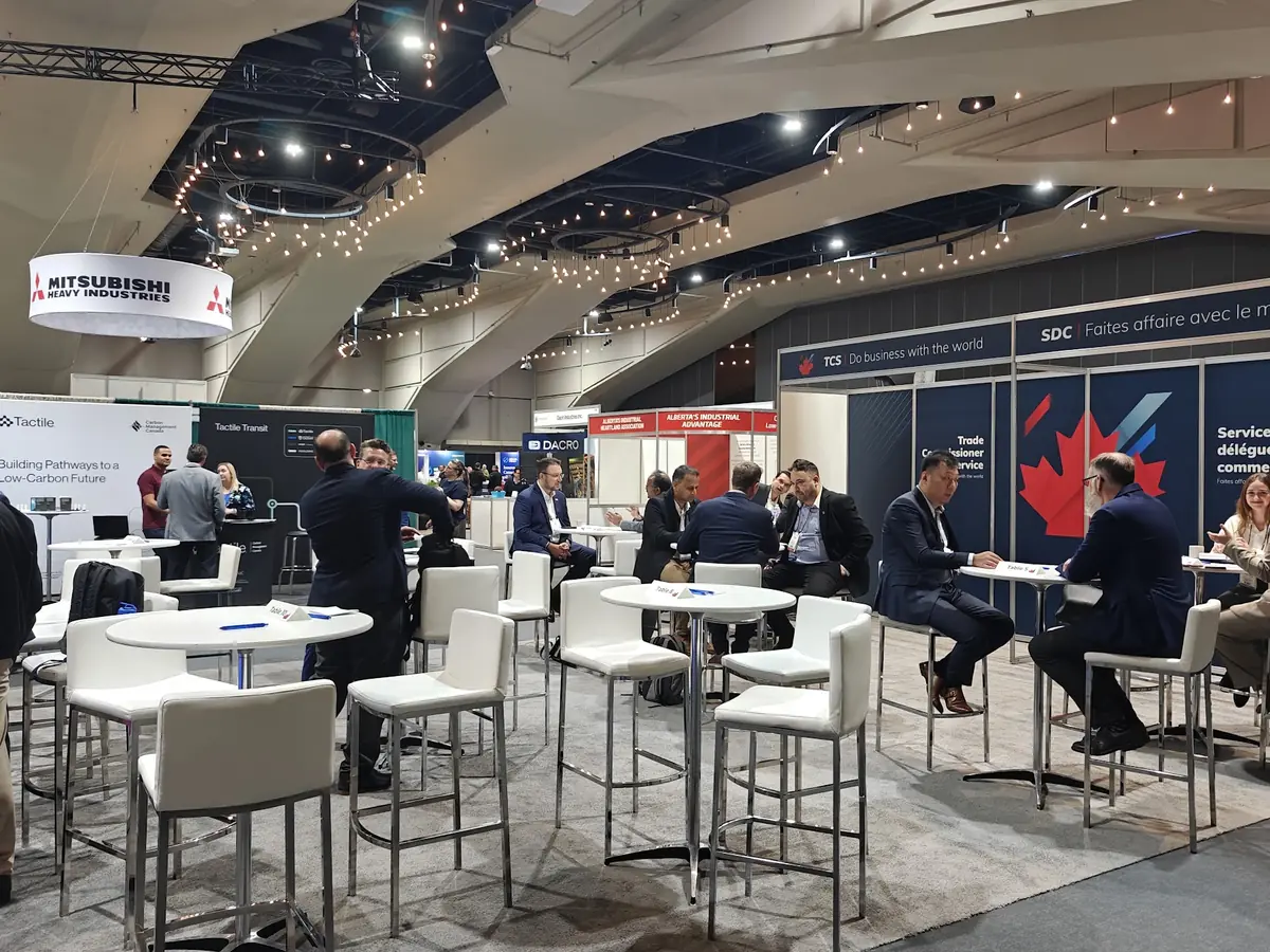 Two attendees holding a scheduled one-on-one B2B meeting at a numbered high-top table on a trade show floor