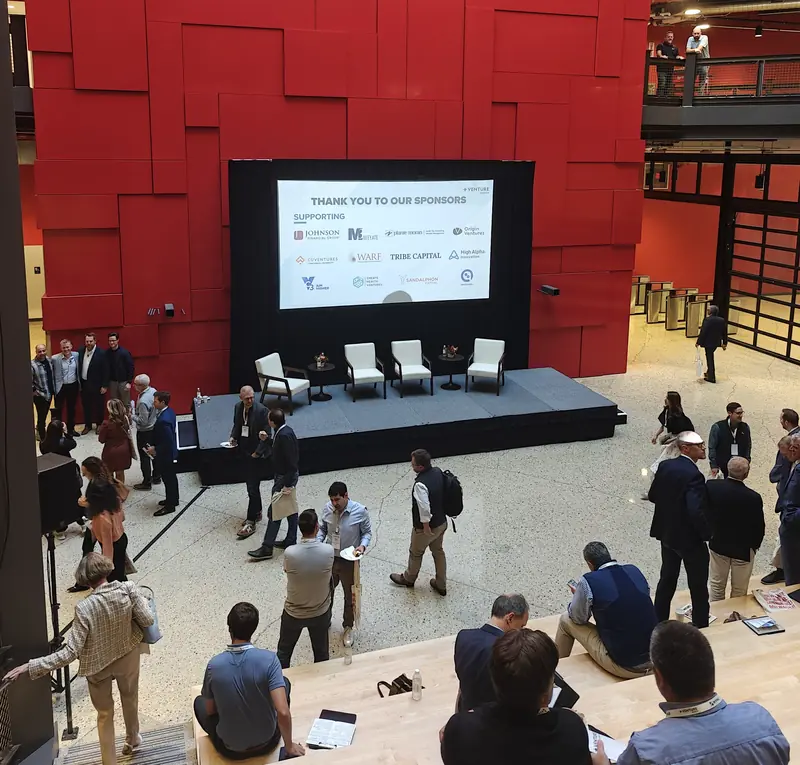 Conference attendees networking in an atrium around a stage between sessions