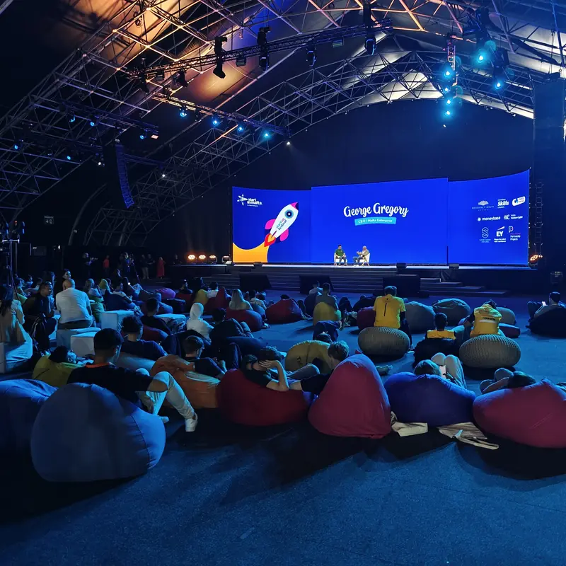 A full audience facing the main stage at a startup festival